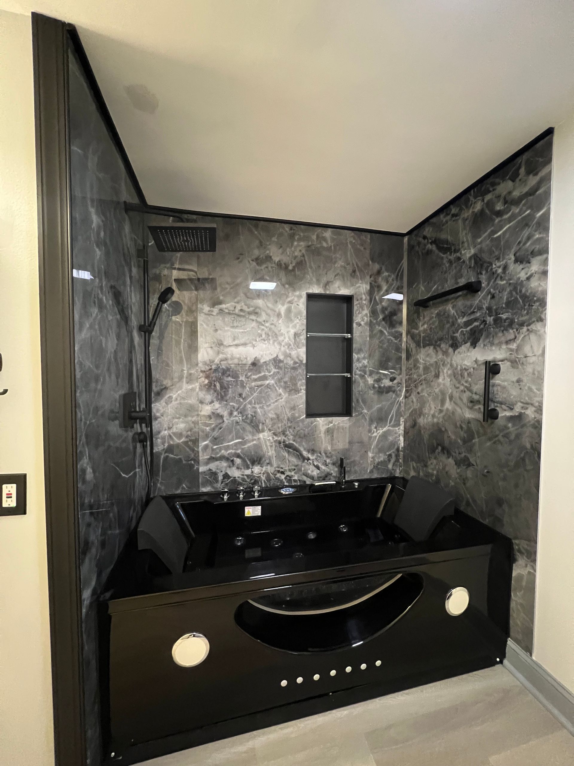 A bathroom with a black tub and a shower.