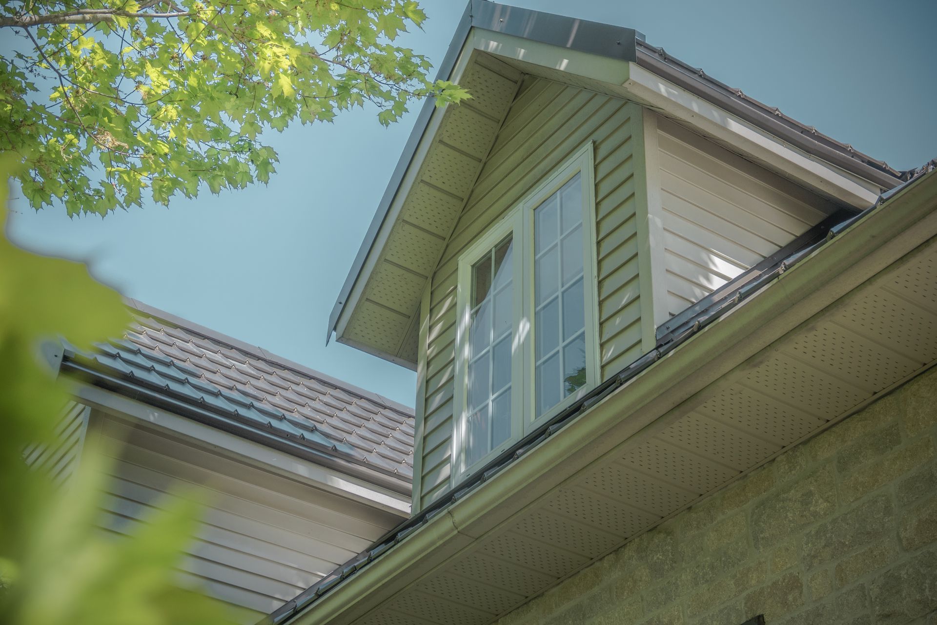 Looking up at the roof of a house with a window.