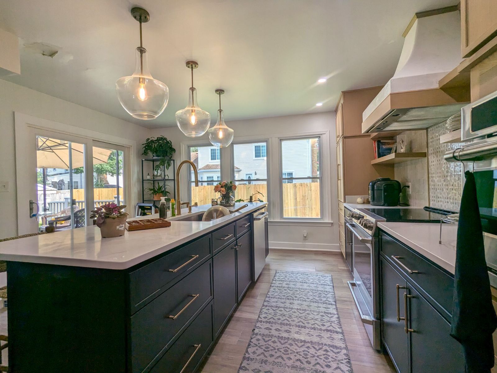 A kitchen with black cabinets , white counter tops , stainless steel appliances and a large island.