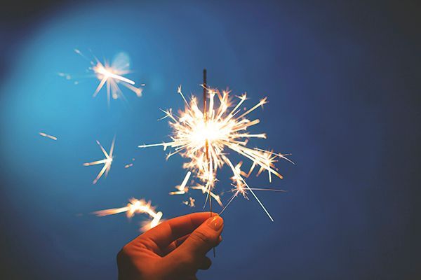 a person is holding a sparkler in their hand against a blue sky .