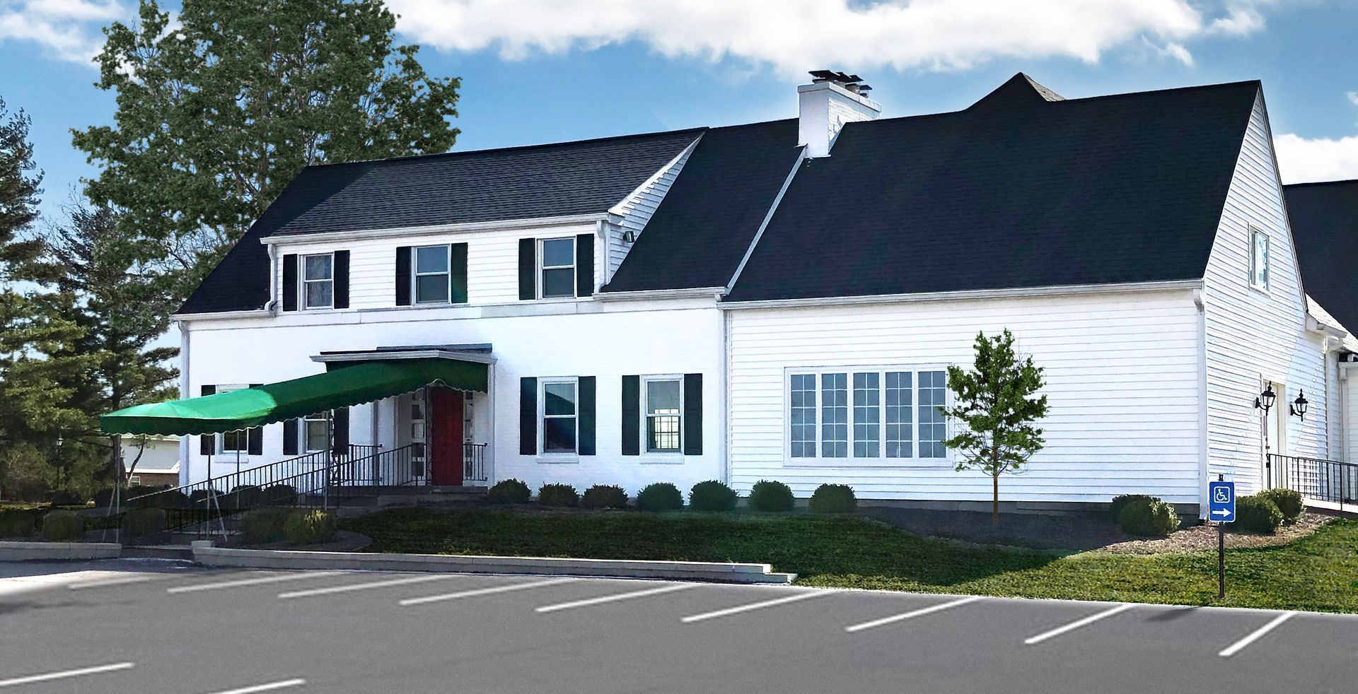 a white house with a black roof and a green awning