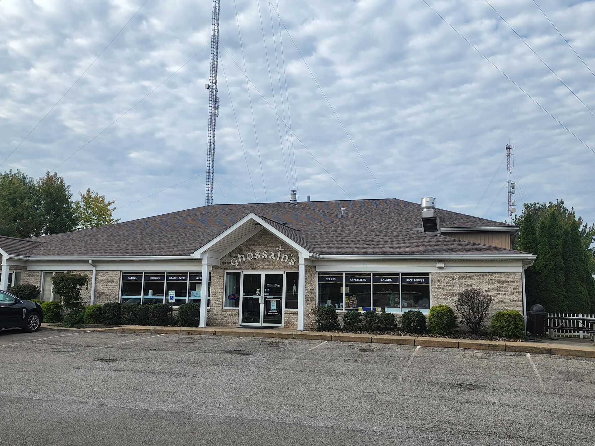 Low brick building with a central entrance, gravel lot, and cloudy sky above