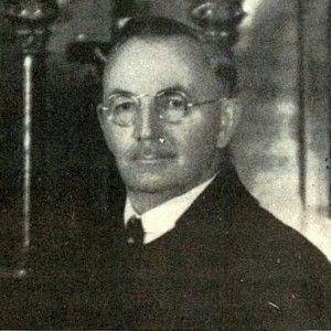 A black and white photo of a man wearing glasses and a suit.