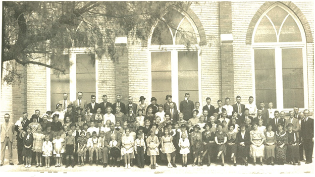 A large group of people are posing for a picture in front of a building.