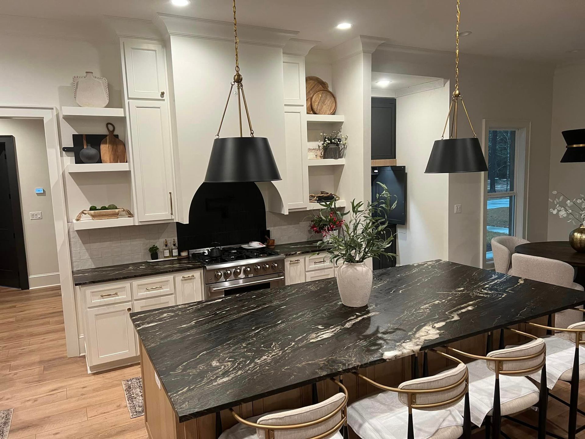 A kitchen with a large black counter top and white cabinets.