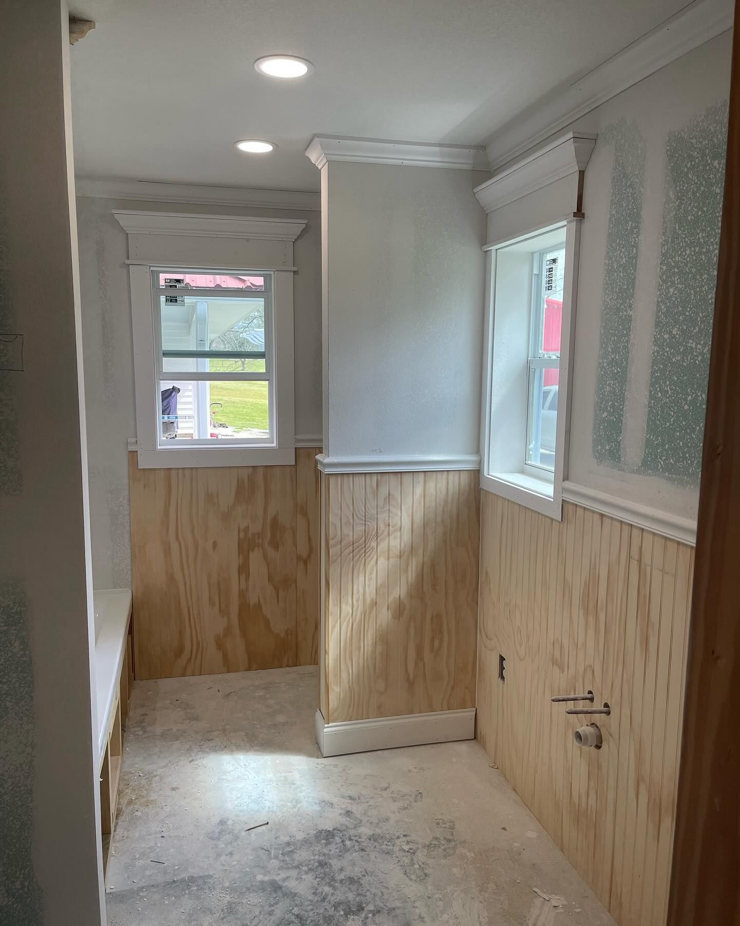 A hallway with wood paneling and a window in a house under construction.
