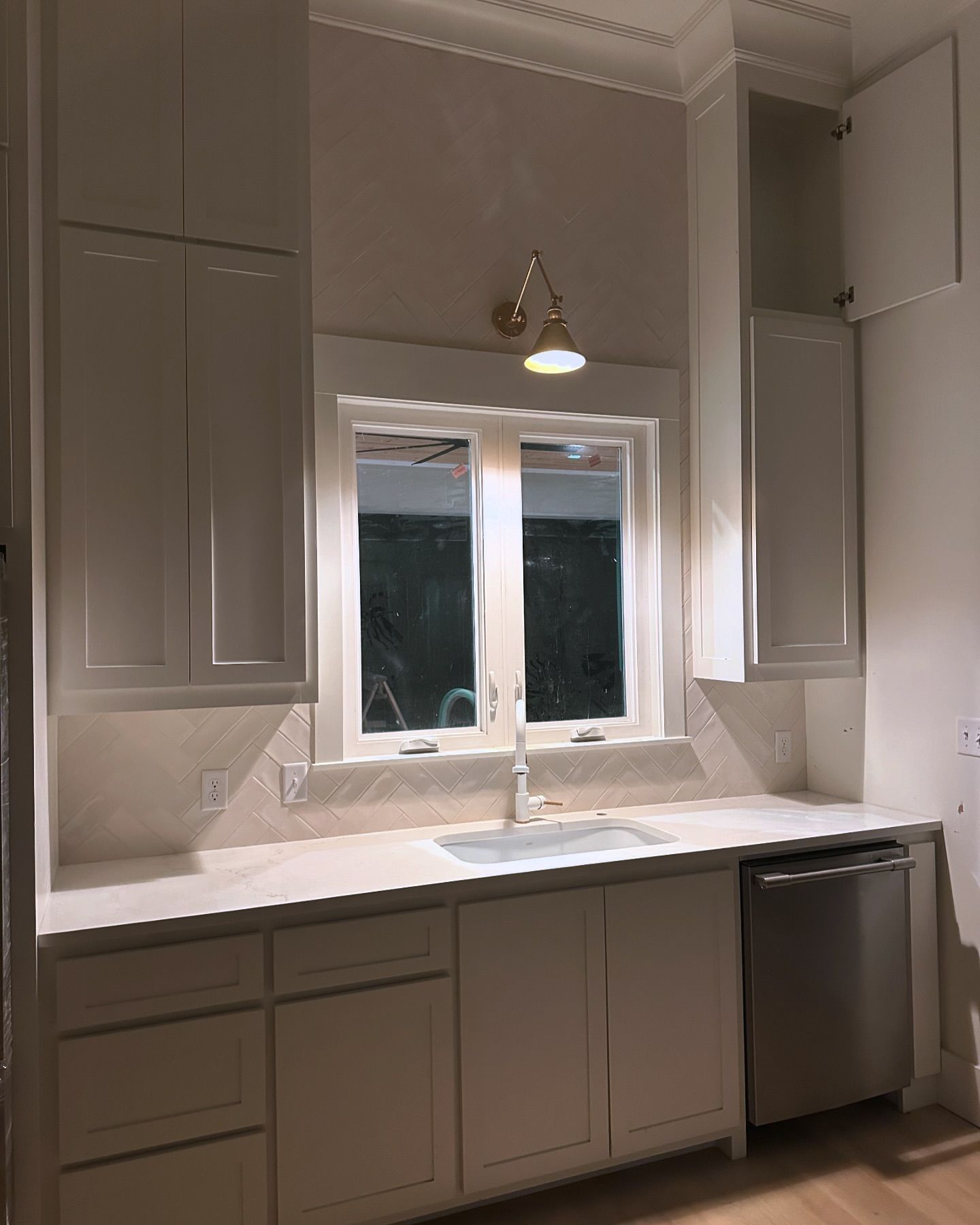 A kitchen with white cabinets a sink and a window