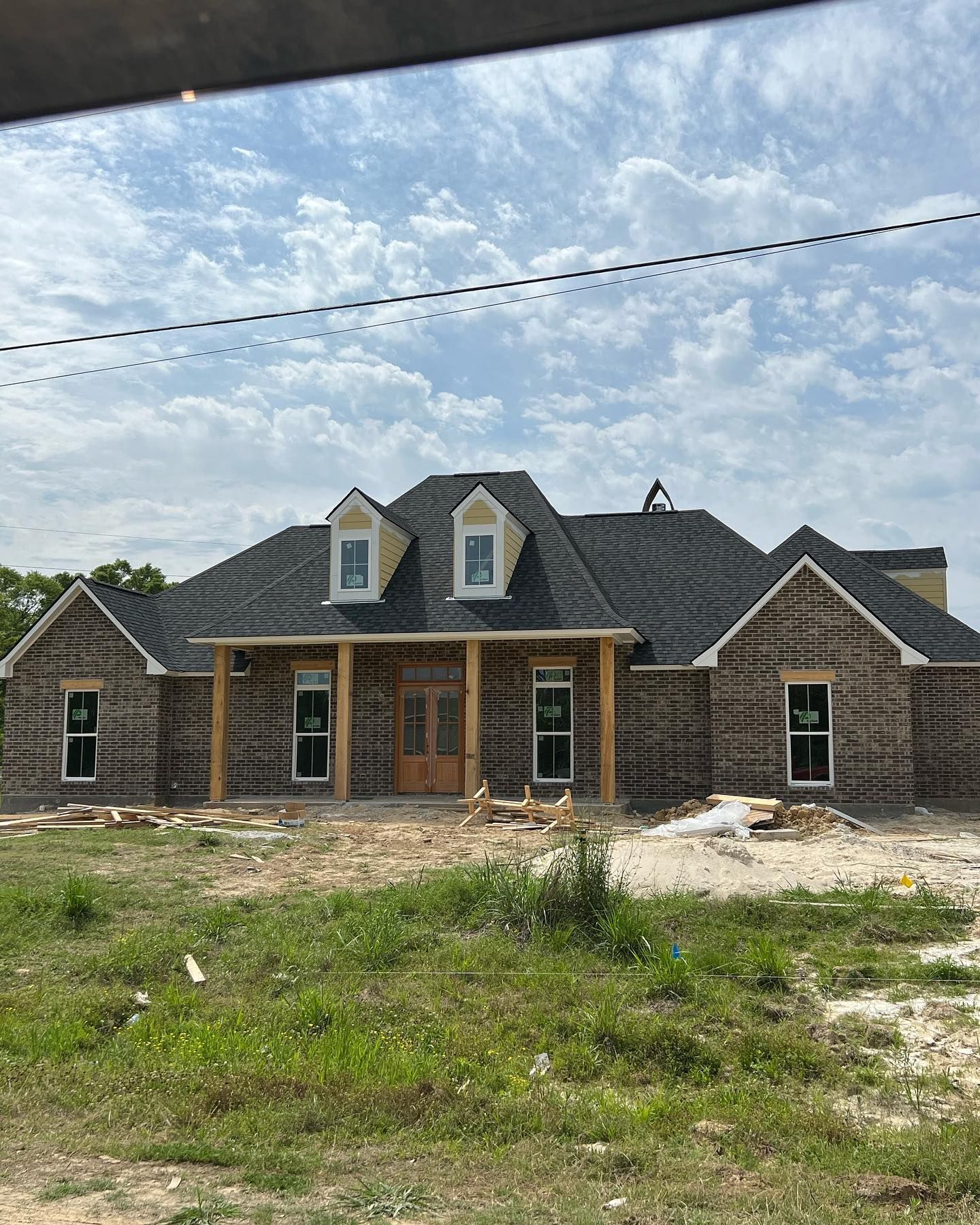A large brick house is being built in the middle of a grassy field.