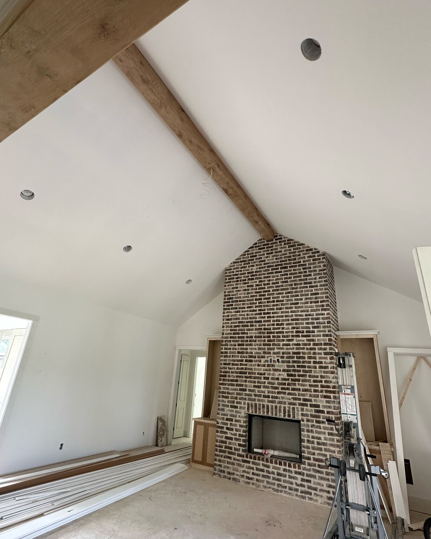A room with a brick fireplace and a vaulted ceiling