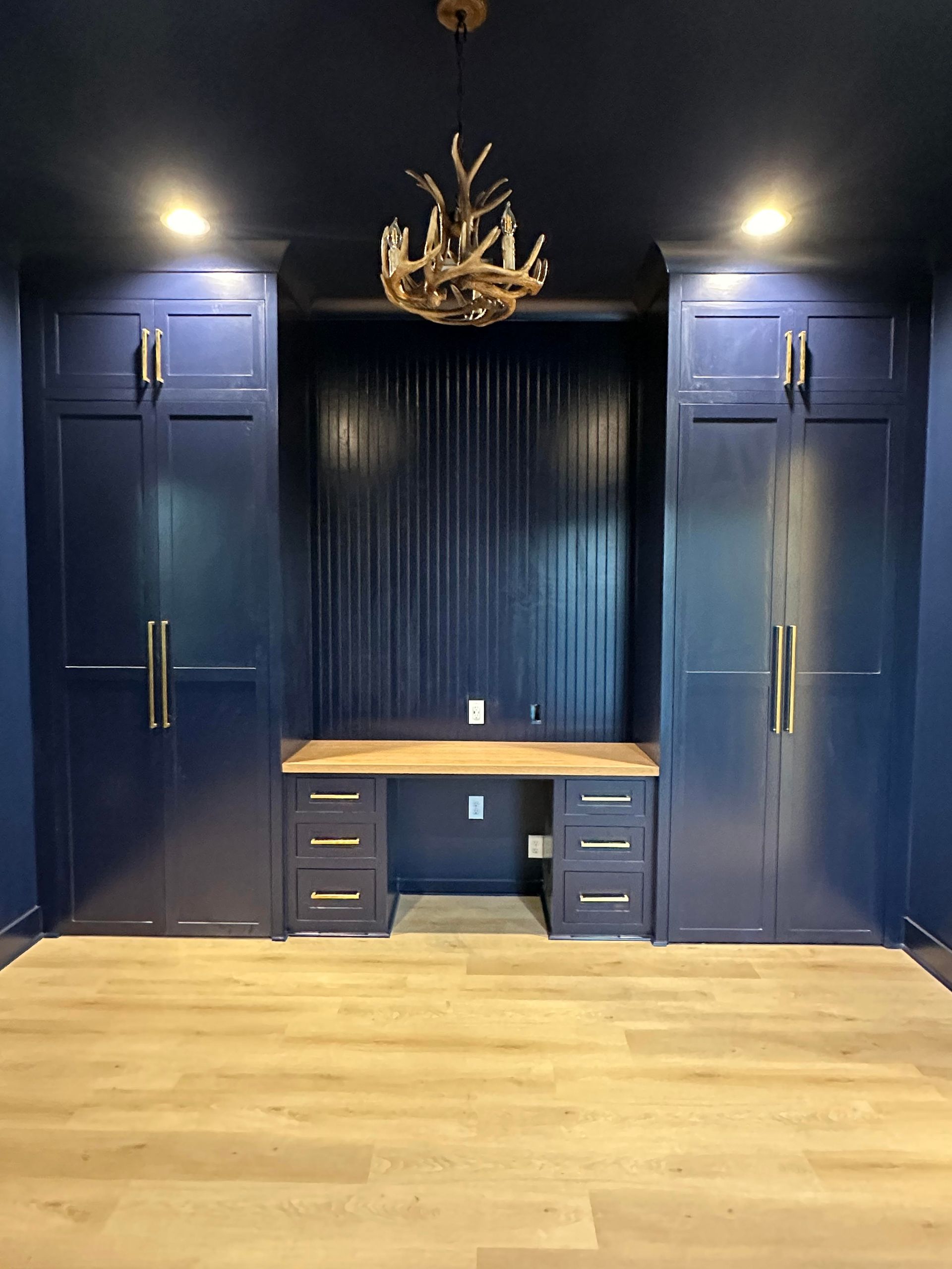 There is a desk in the middle of the room with a chandelier hanging from the ceiling.