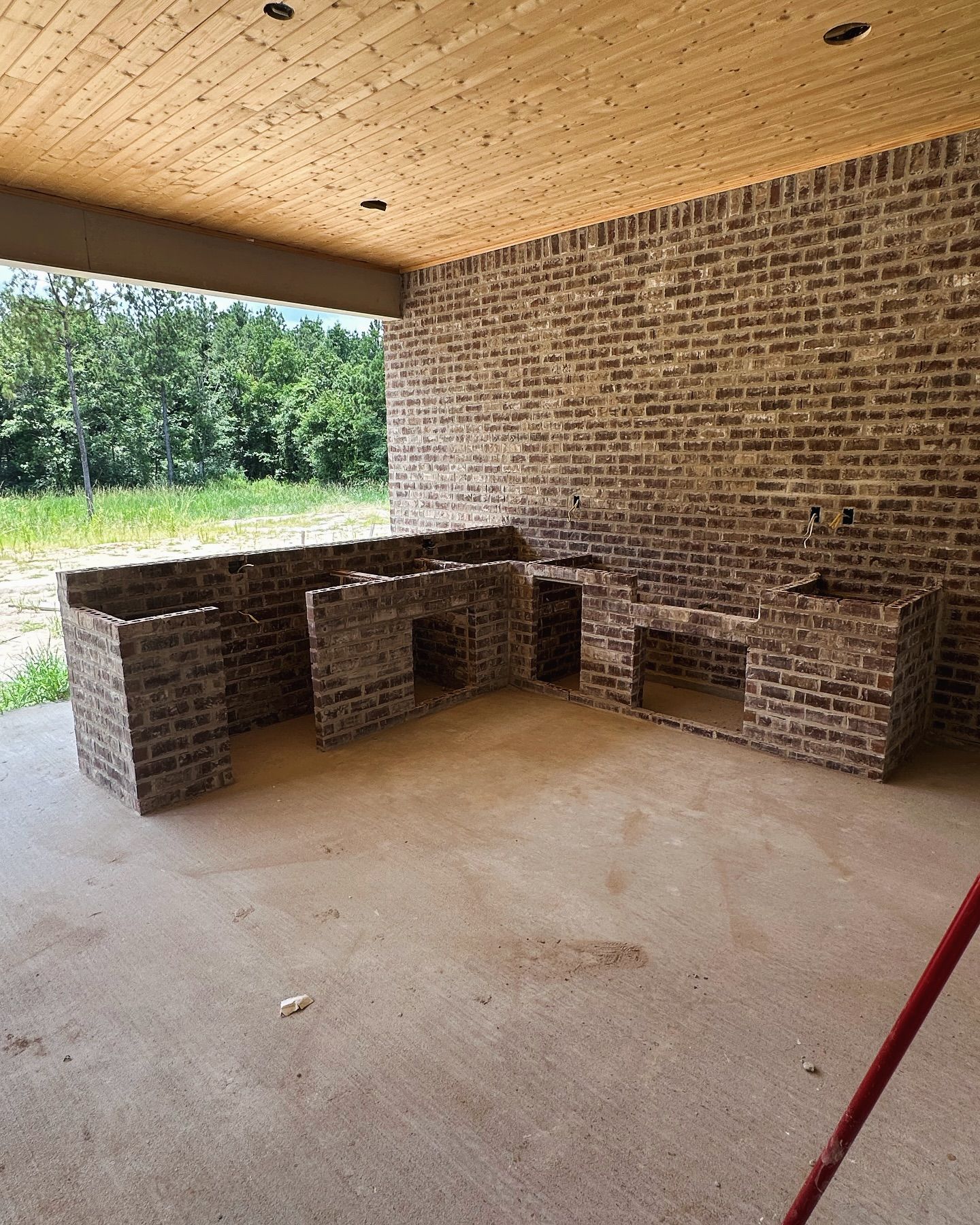 A brick wall with a wooden ceiling and a broom in the foreground.