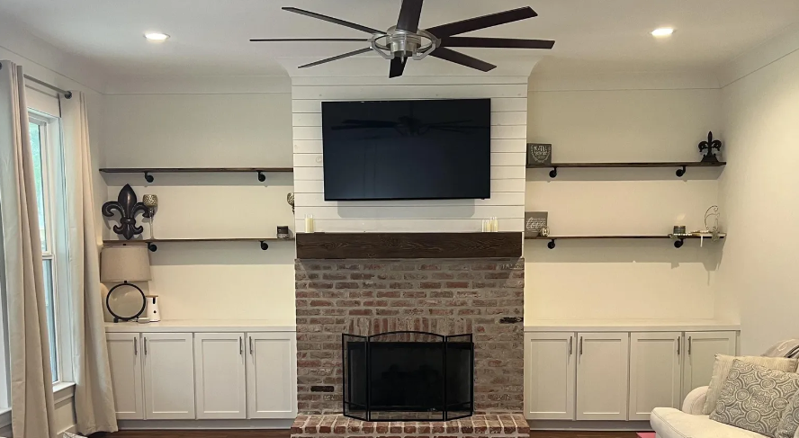 A living room with a fireplace and a flat screen tv on the wall.
