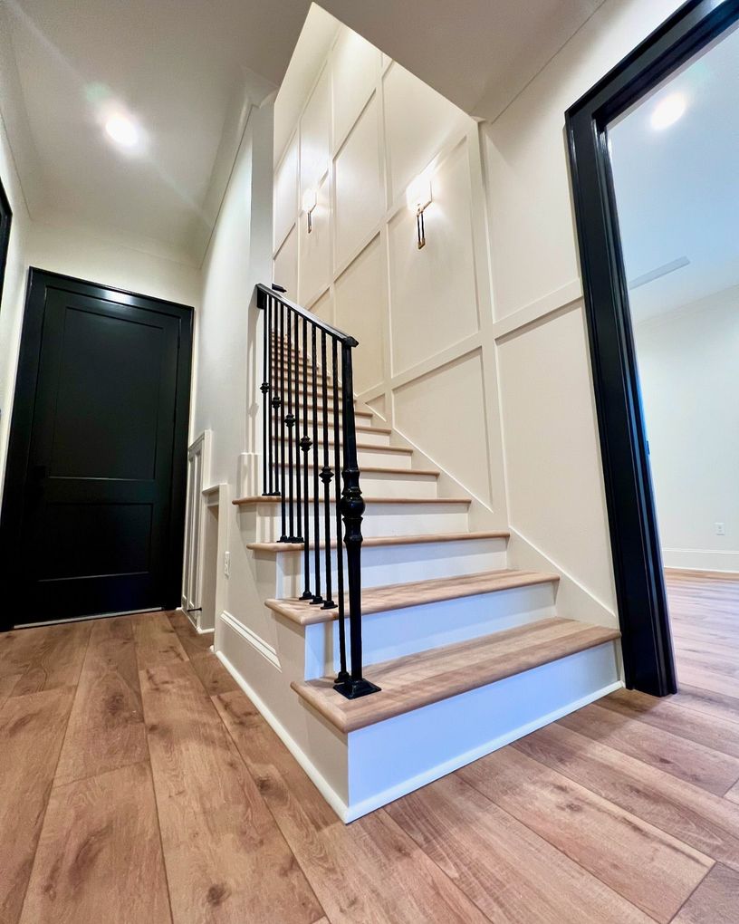 A staircase with wooden steps and a black railing in a hallway.