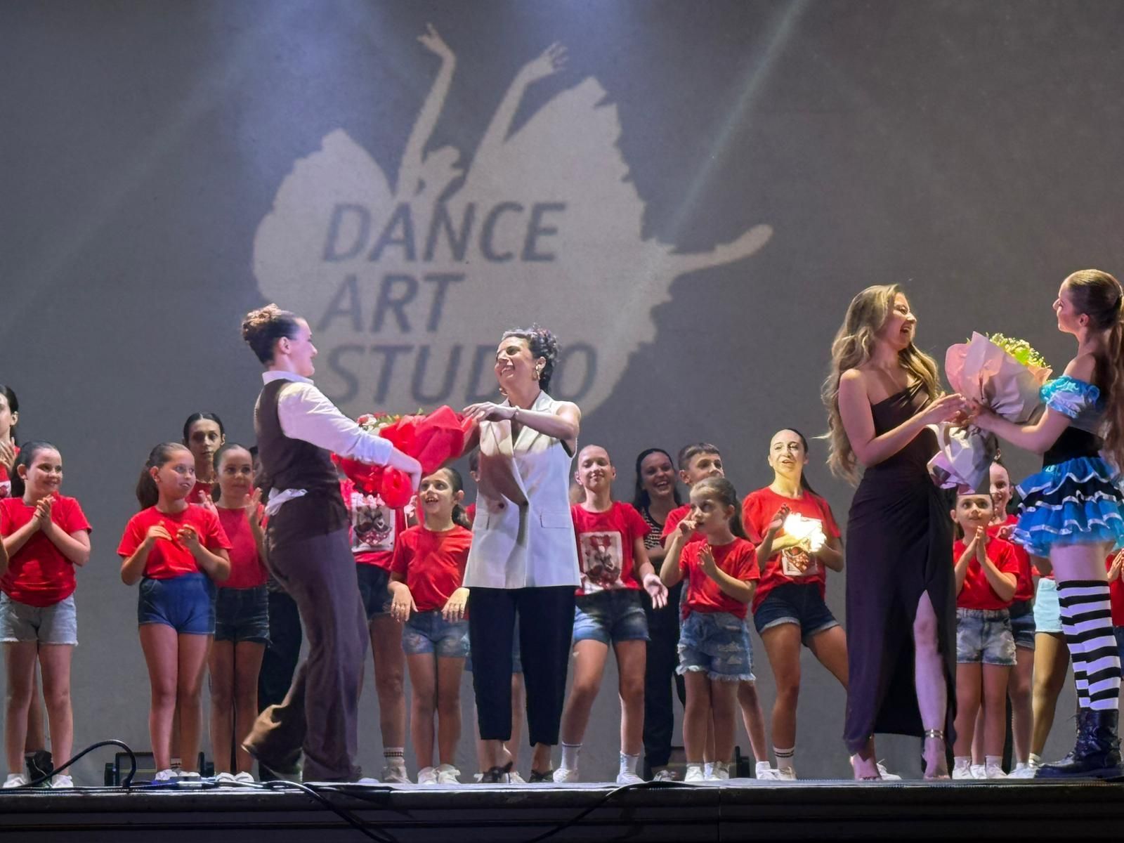 Saggio di danza: gli artisti sul palco donano fiori al pubblico.
