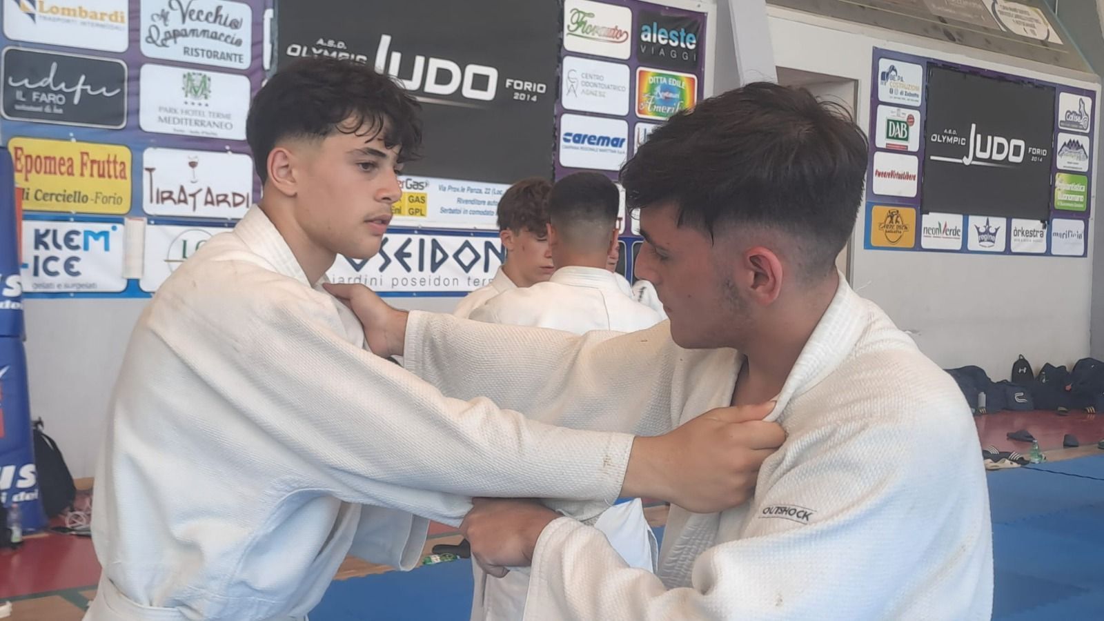Due praticanti di judo in kimono bianco praticano una tecnica di lotta al chiuso.