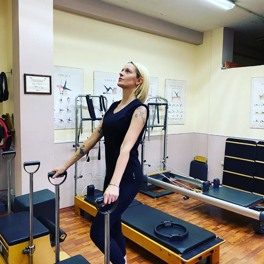 Donna in una sala Pilates, con in mano un attrezzo e lo sguardo rivolto verso l'alto.