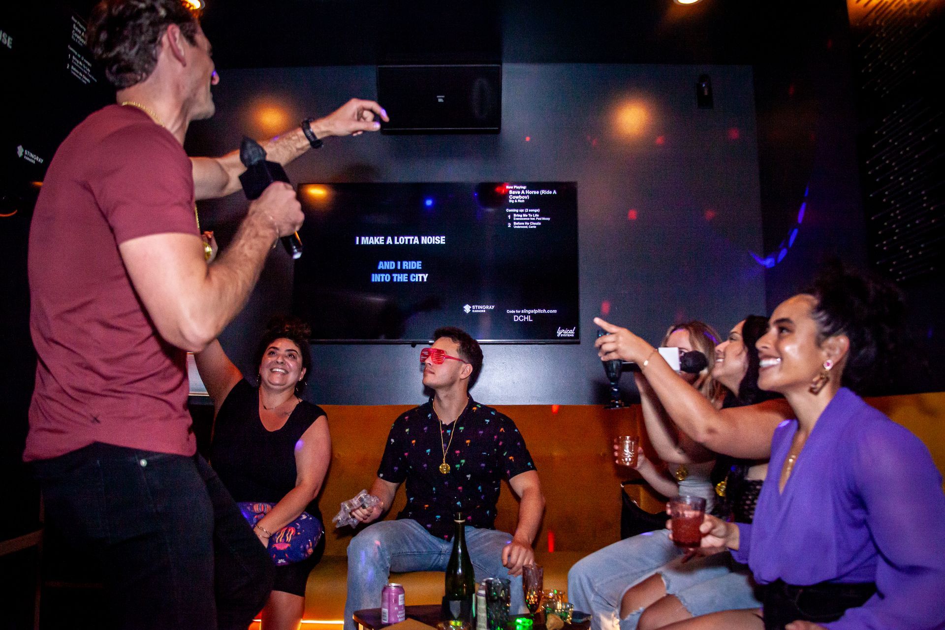 Friends cheer on someone singing karaoke in a private suite