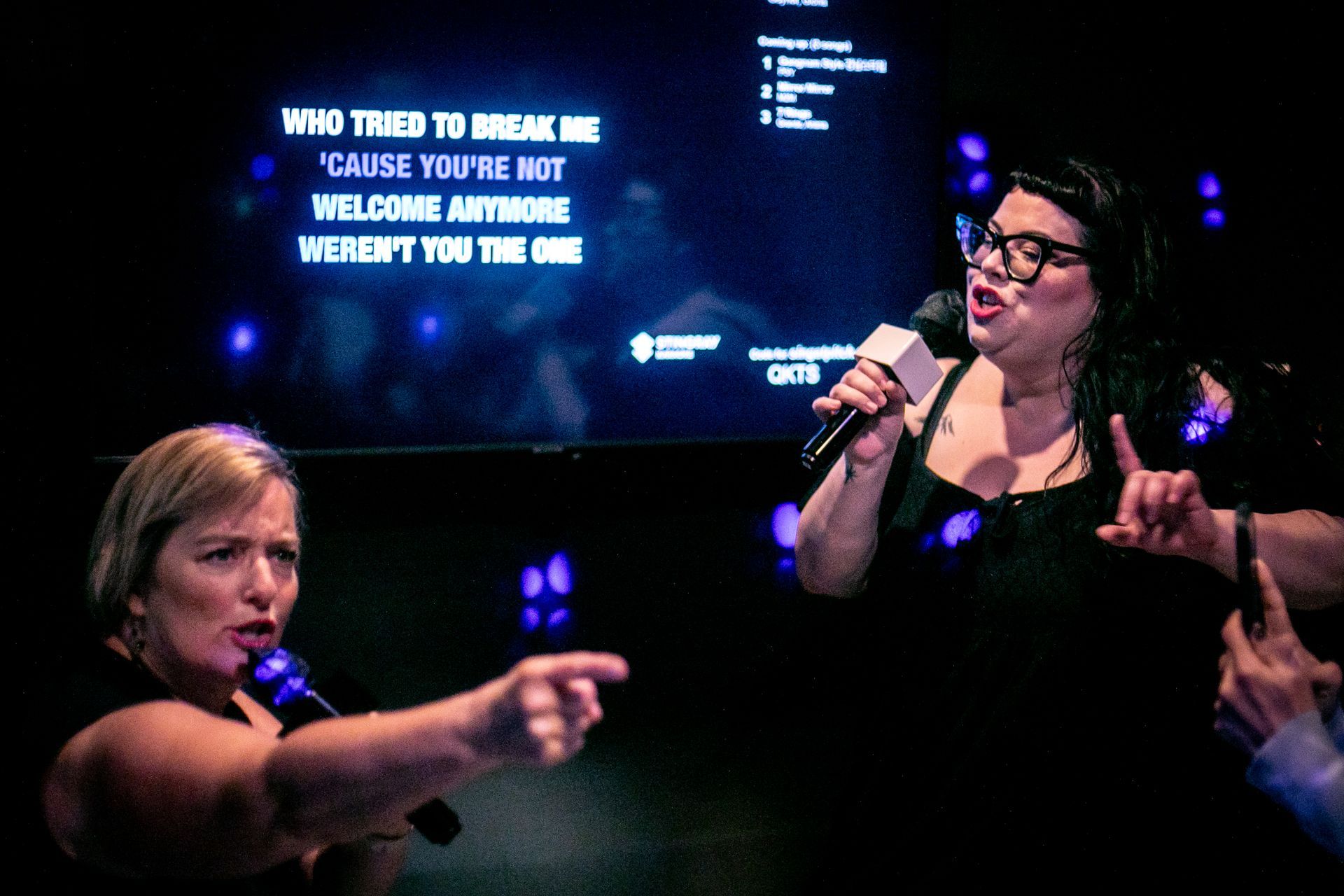 Friends having fun singing a duet in a private suite at pitch karaoke