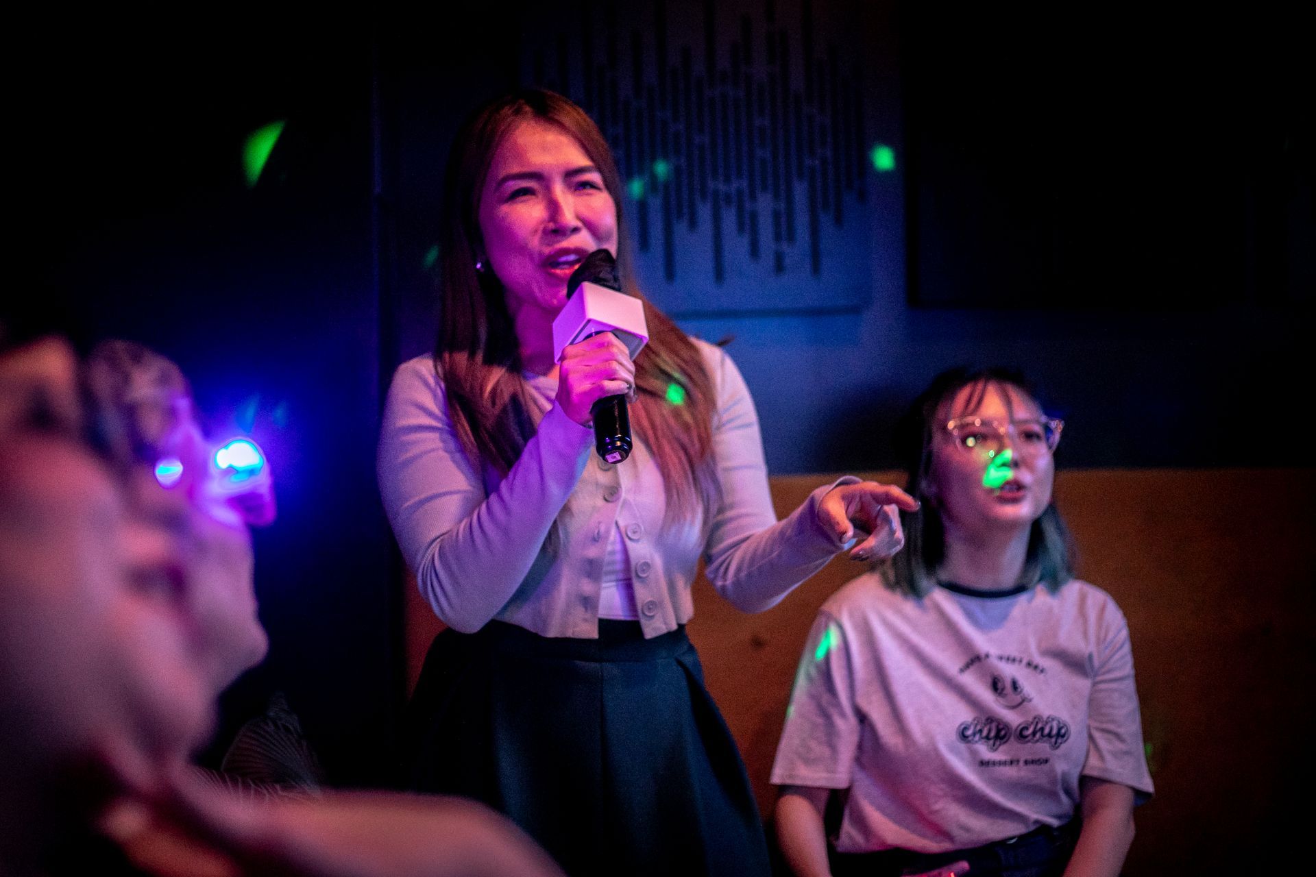 Singer taking on a karaoke solo while her friends watch in a private suite.