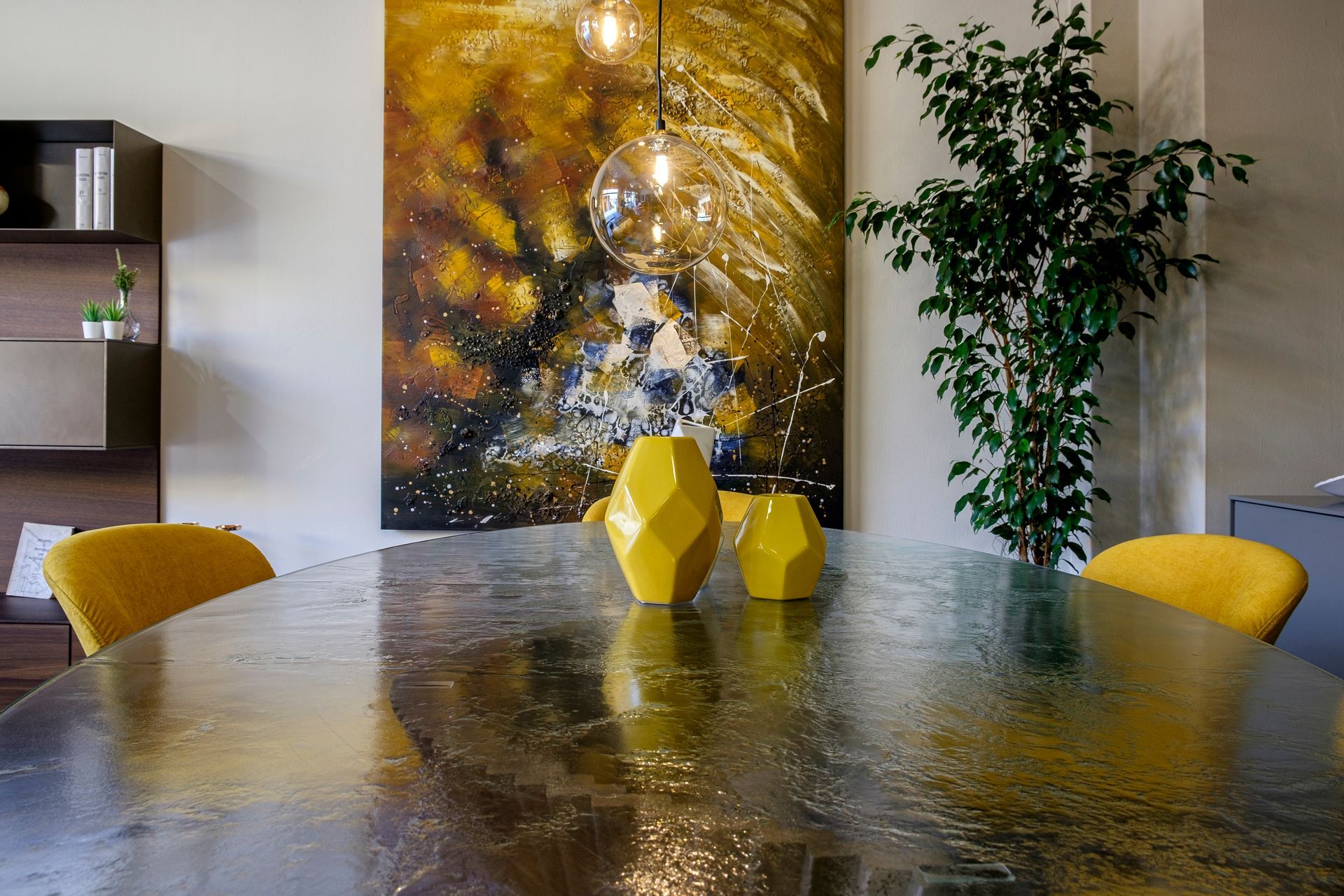 Un tavolo da pranzo con sedie gialle e un quadro alla parete.