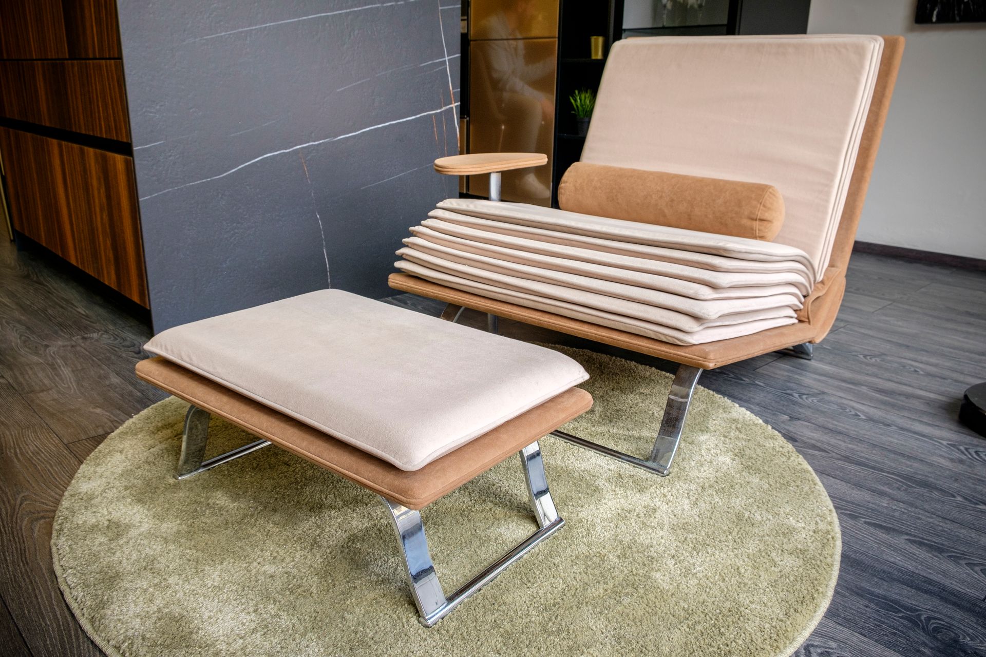 Una sedia e un pouf sono appoggiati su un tappeto rotondo.