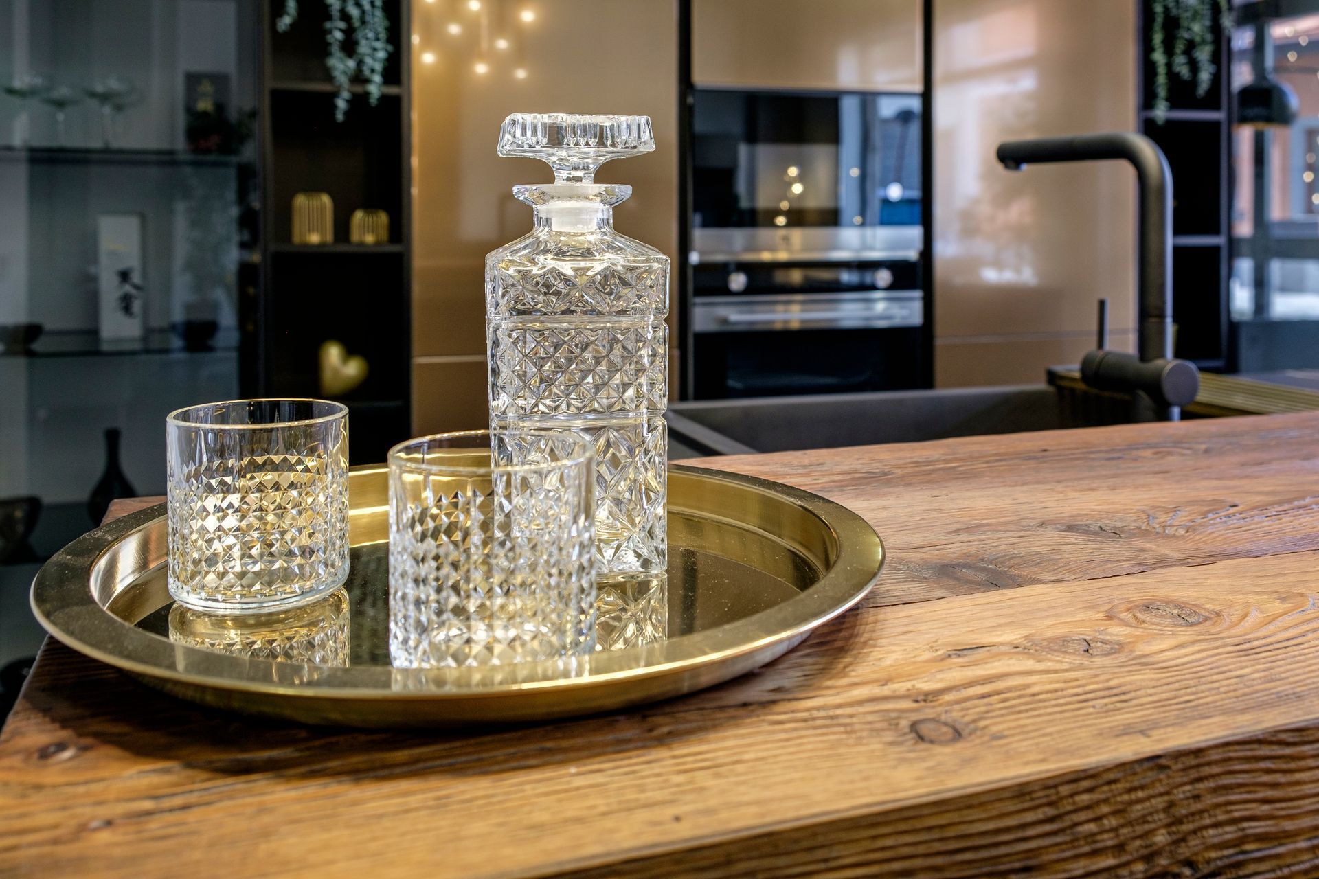 Una caraffa e due bicchieri sono su un vassoio su un bancone di legno.