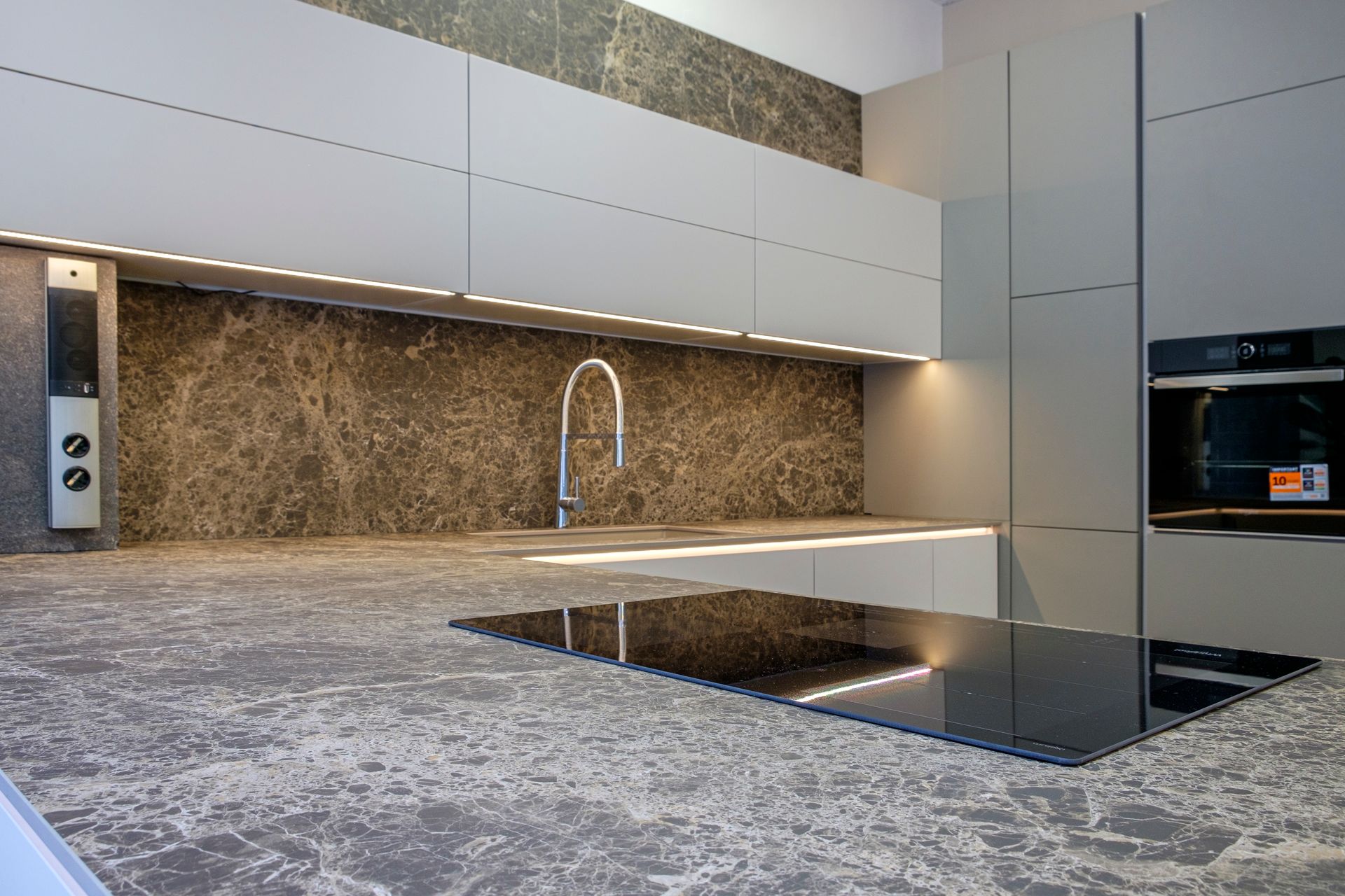 Una cucina con lavello, piano cottura, forno e ripiani in marmo.