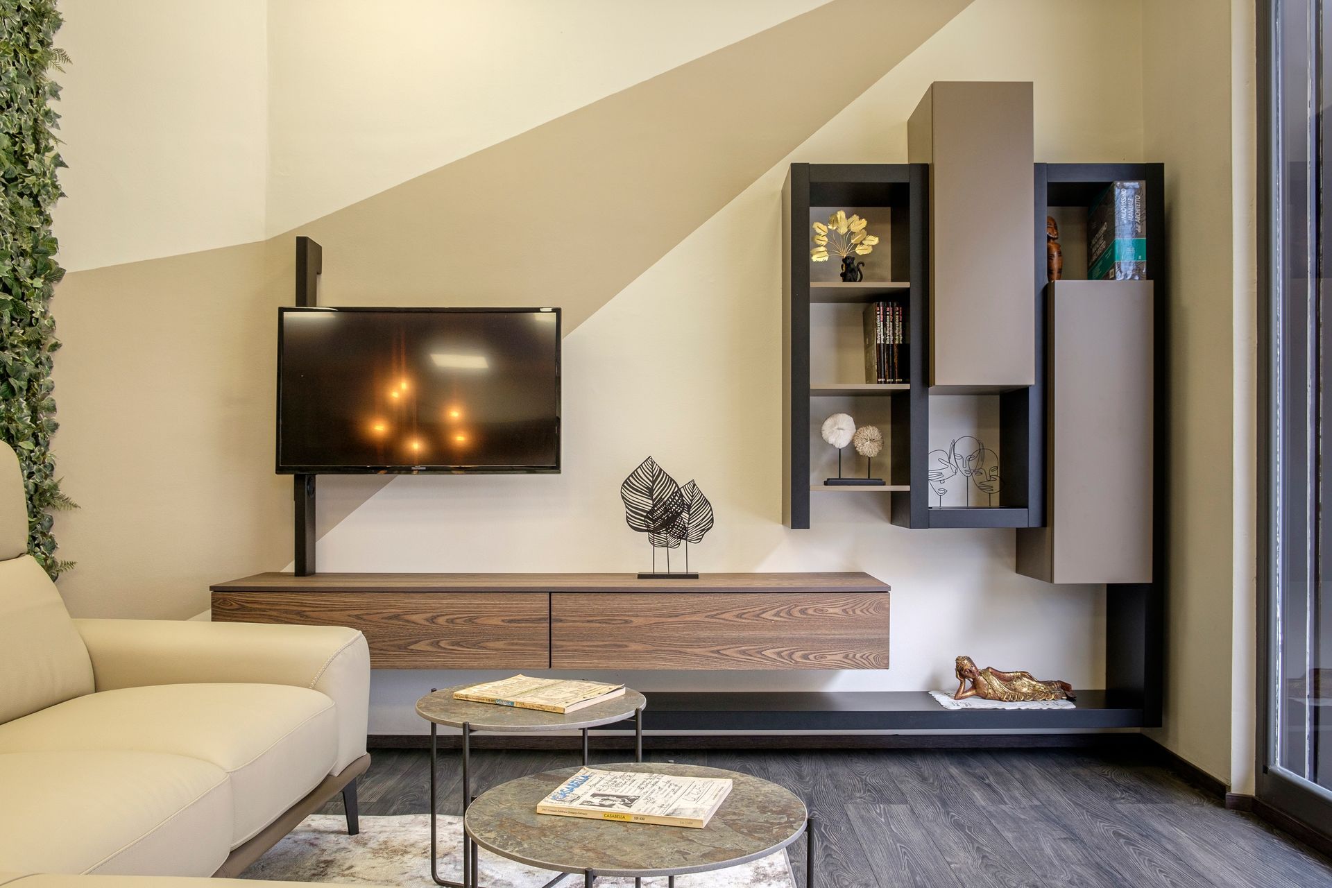 Un soggiorno con divano, tavolo, televisione e scaffali.