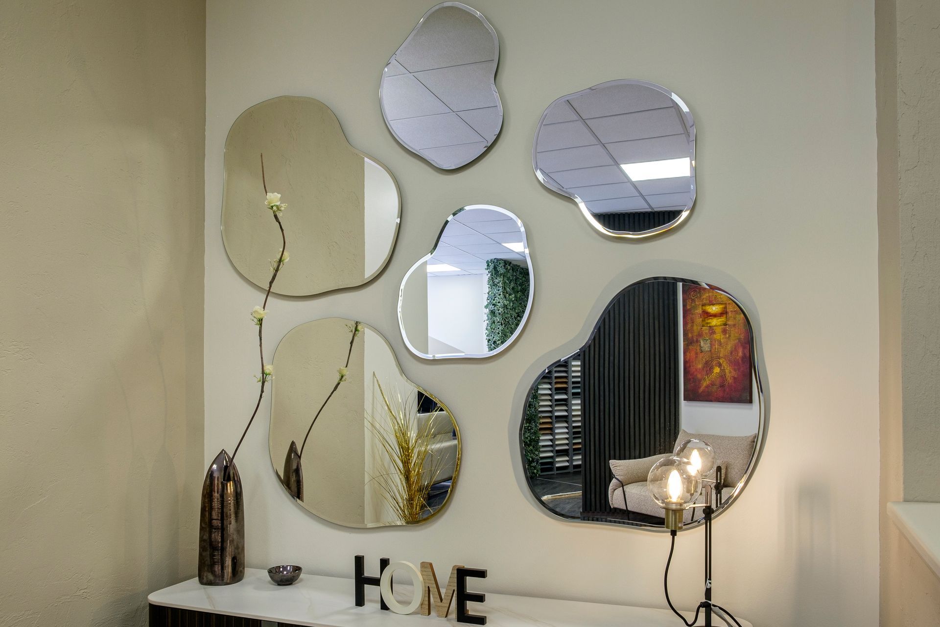 Un gruppo di specchi è appeso a una parete accanto a un cartello che dice casa.
