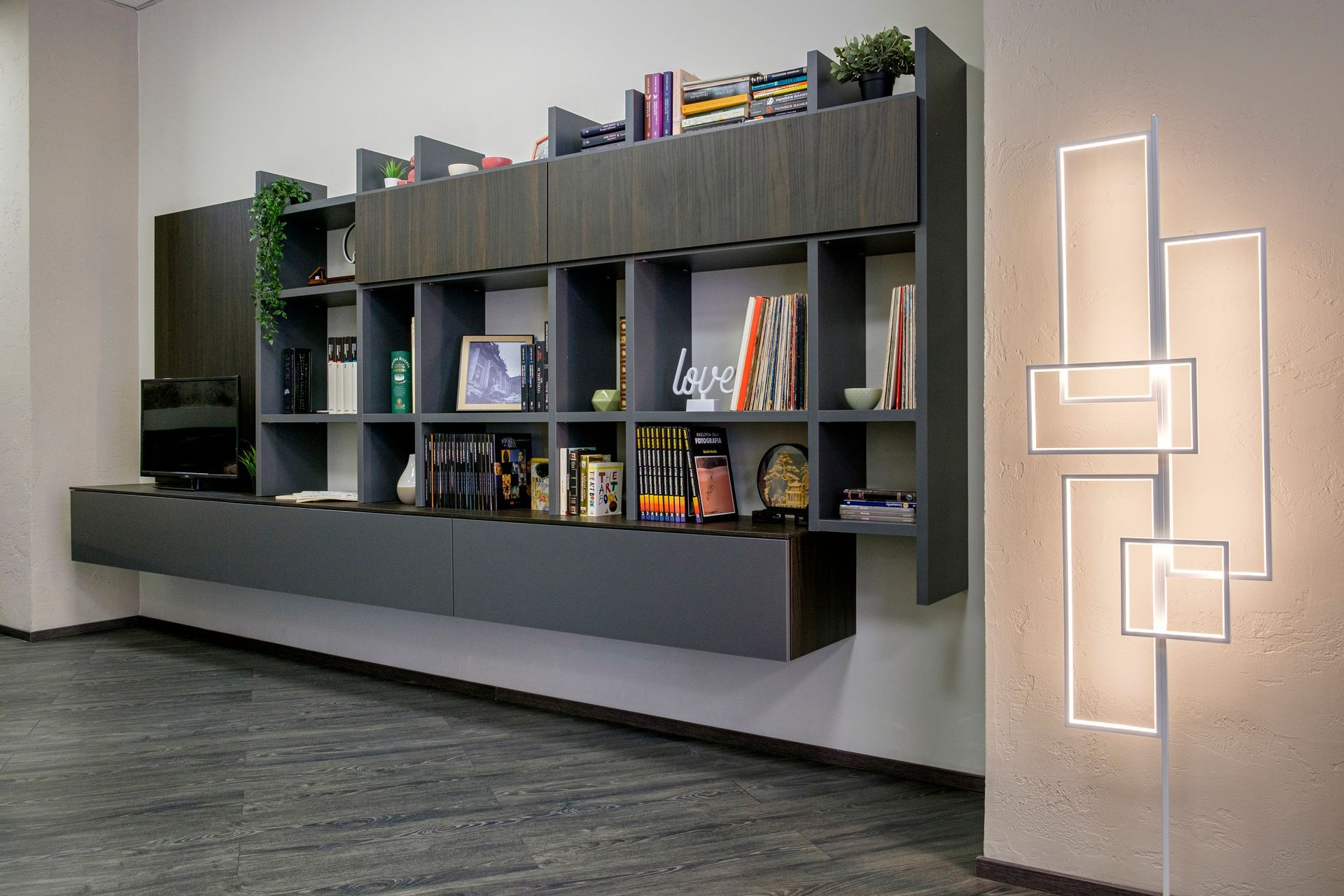 Un soggiorno con uno scaffale pieno di libri e una lampada alla parete.