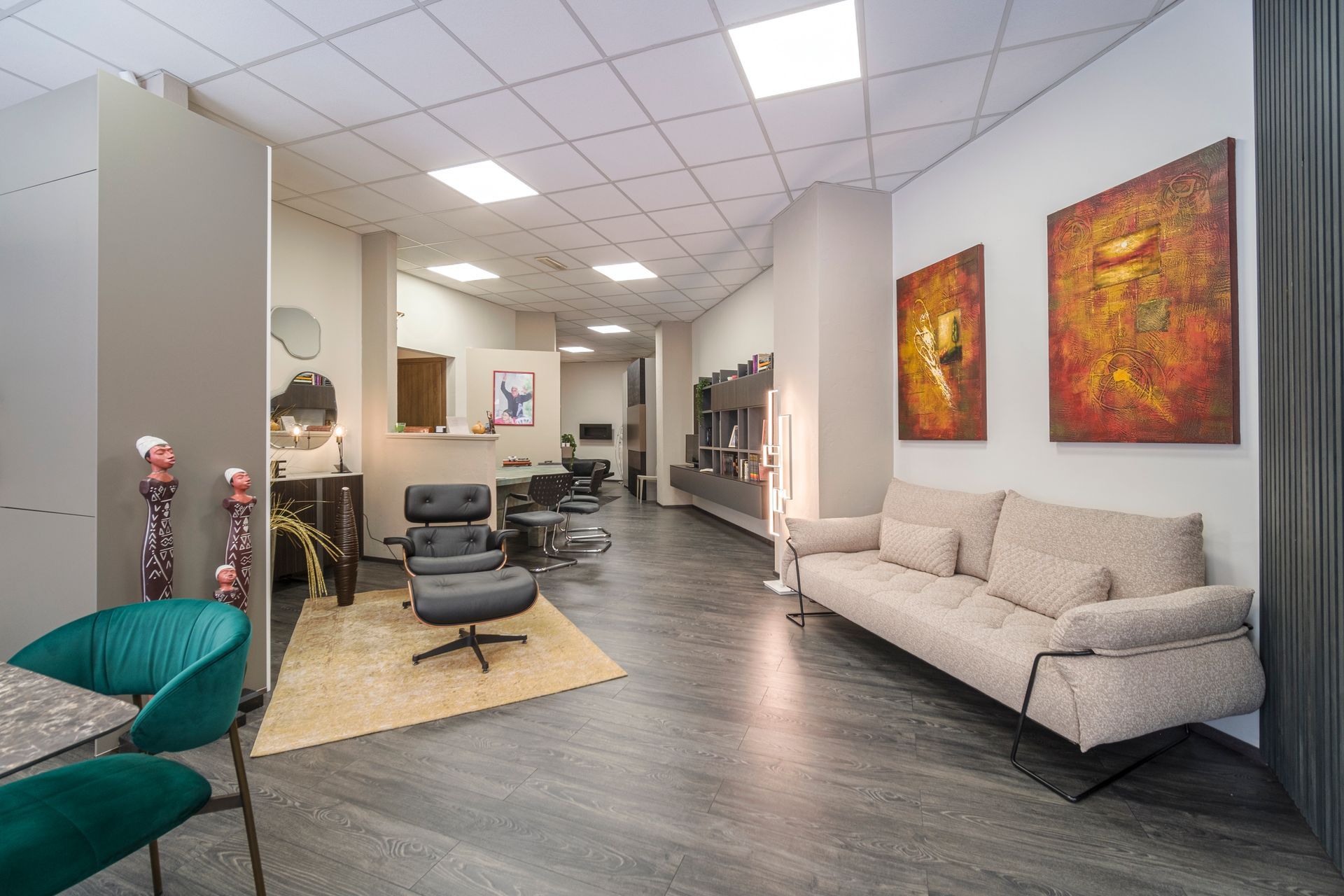 Un soggiorno con divano, sedie, pouf e quadri alle pareti.