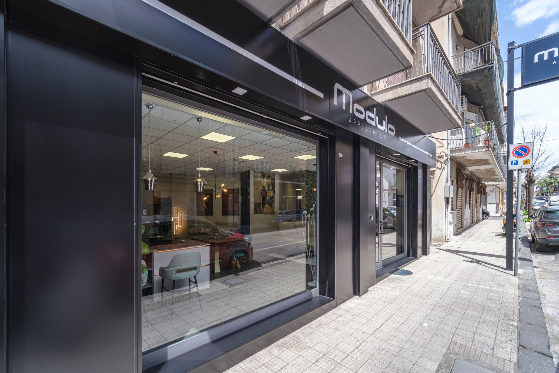 Una vetrina con tante vetrine e un'auto parcheggiata davanti.