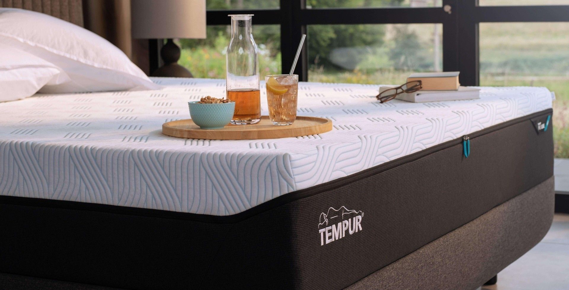 Un materasso Tempur è posizionato sopra un letto accanto a una finestra.