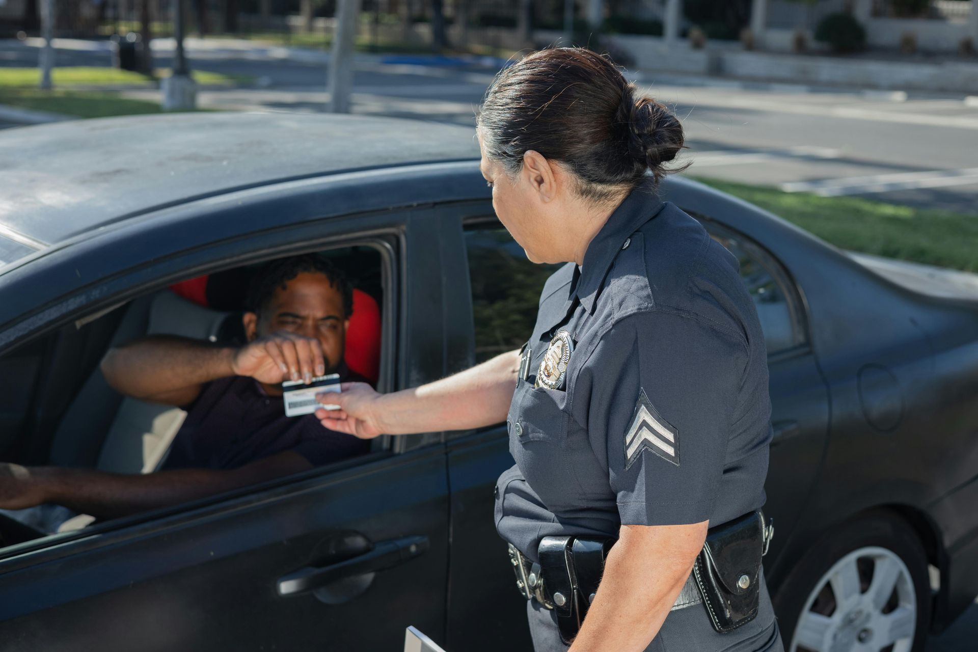 A police officer is giving a ticket to a man in a car.
