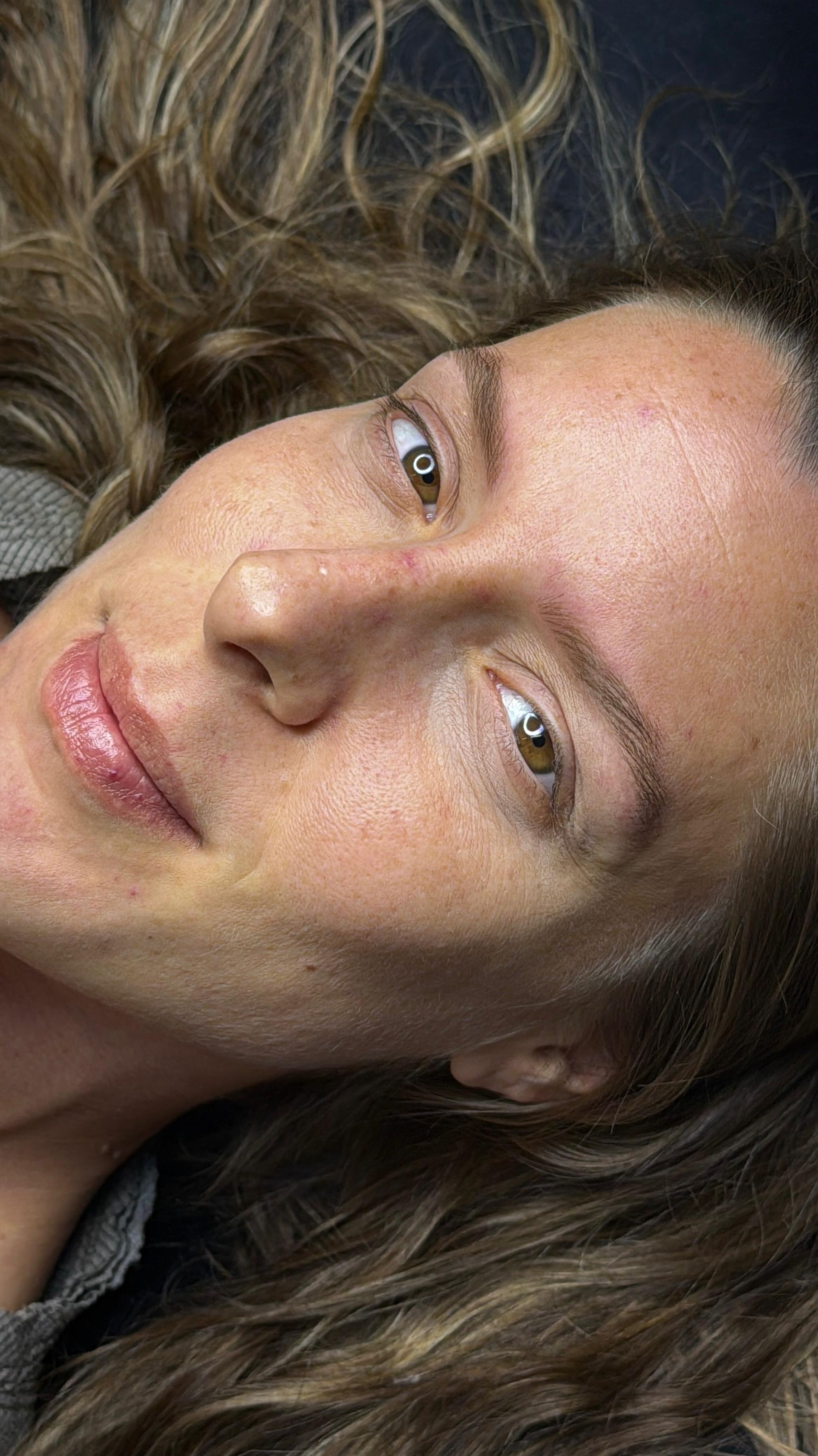 Primer plano, tomado en ángulo, de una persona con cabello largo y ondulado, mirando hacia arriba con expresión neutra.