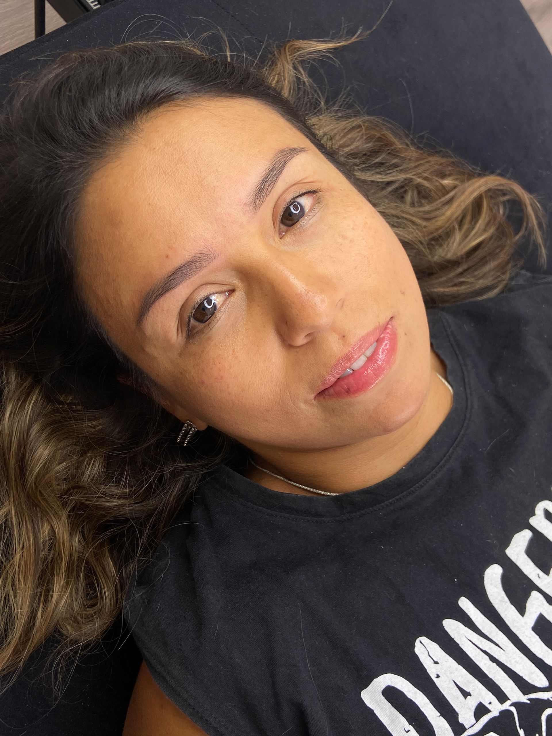 Una persona yace con expresión neutra, dejando ver sus cejas recién tatuadas contra su piel.