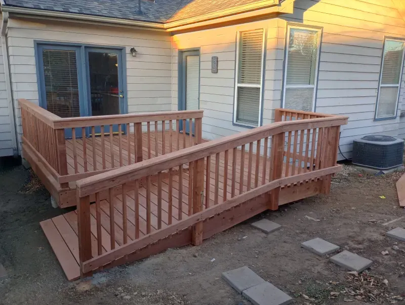 Wooden deck with ramp attached to a house with an air conditioning unit.