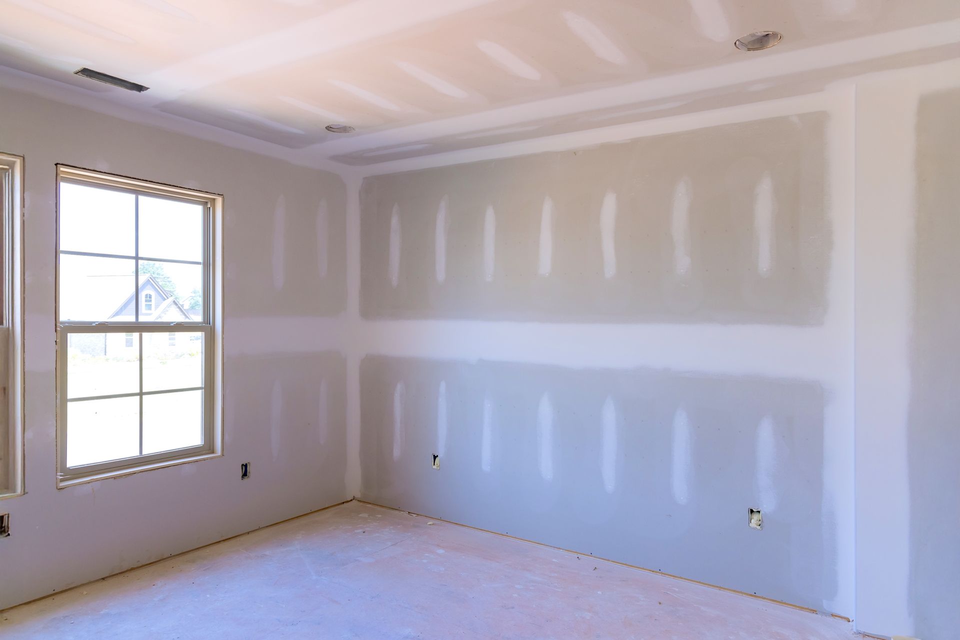 Room under construction, with drywall walls, window, and unfinished ceiling.