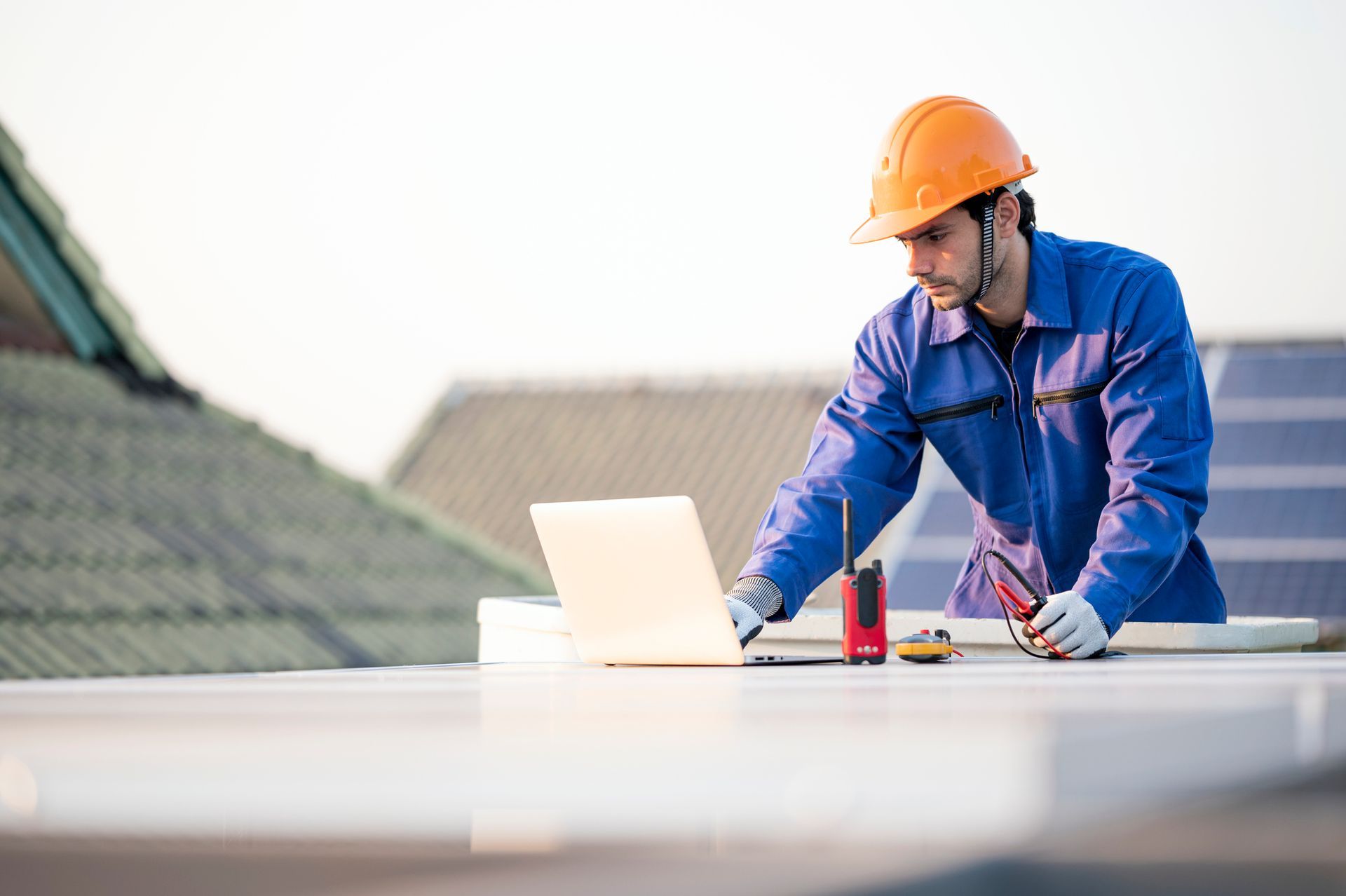 A man is working on a laptop computer on a roof.