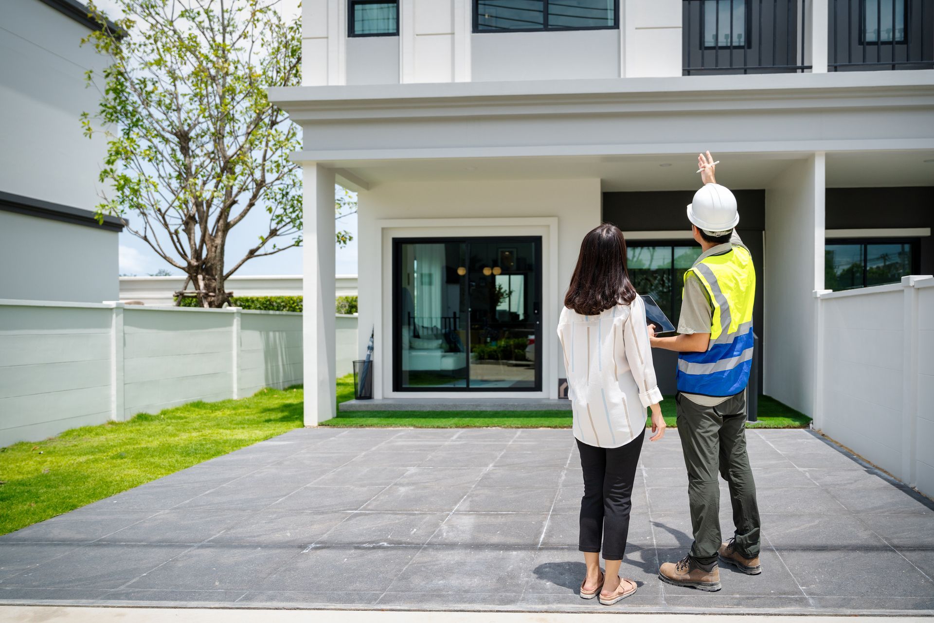 A man and a woman are standing in front of a house.