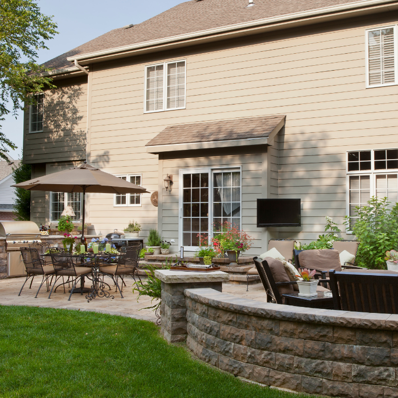Two women at a table in a bright office, working on laptops. A sofa and chairs are nearby.