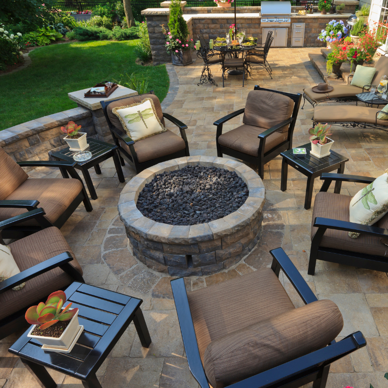 A person in green work clothes is laying pavers, outdoor setting.