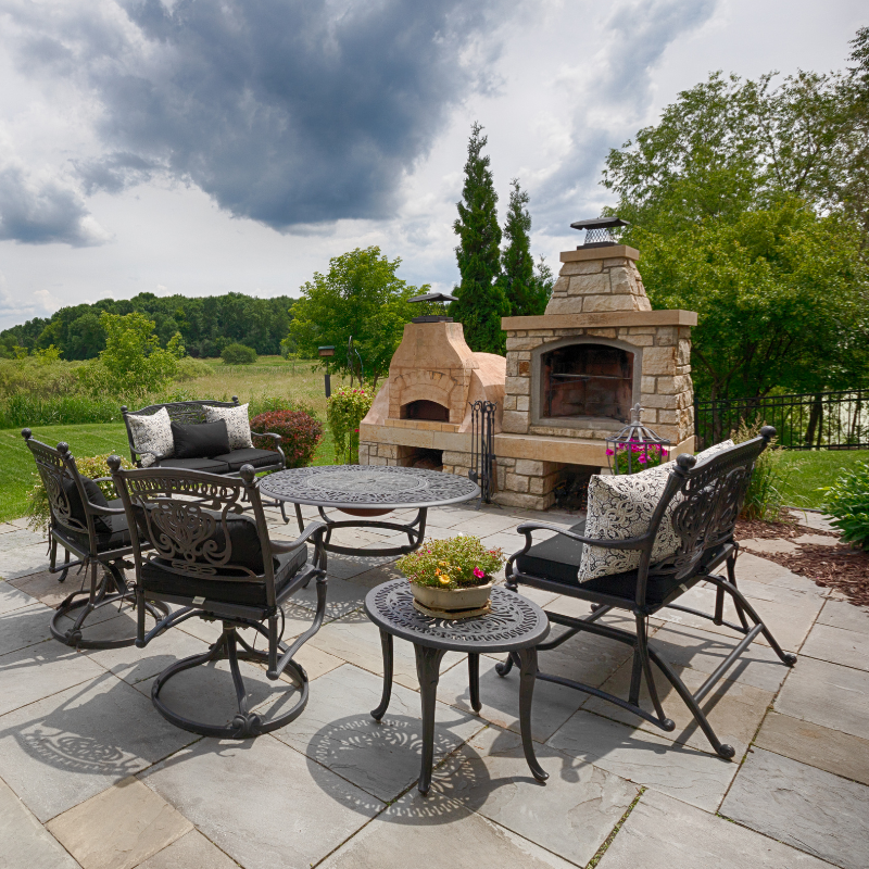 People playing cornhole on a rooftop patio with artificial turf, drinks, and city views.