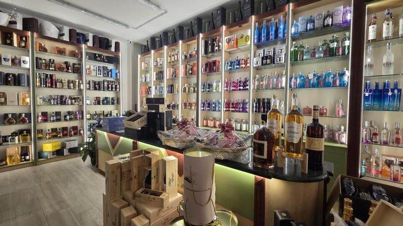 L'interno di un negozio di liquori ben illuminato, con diverse bottiglie esposte sugli scaffali. In primo piano, un bancone con i prodotti.