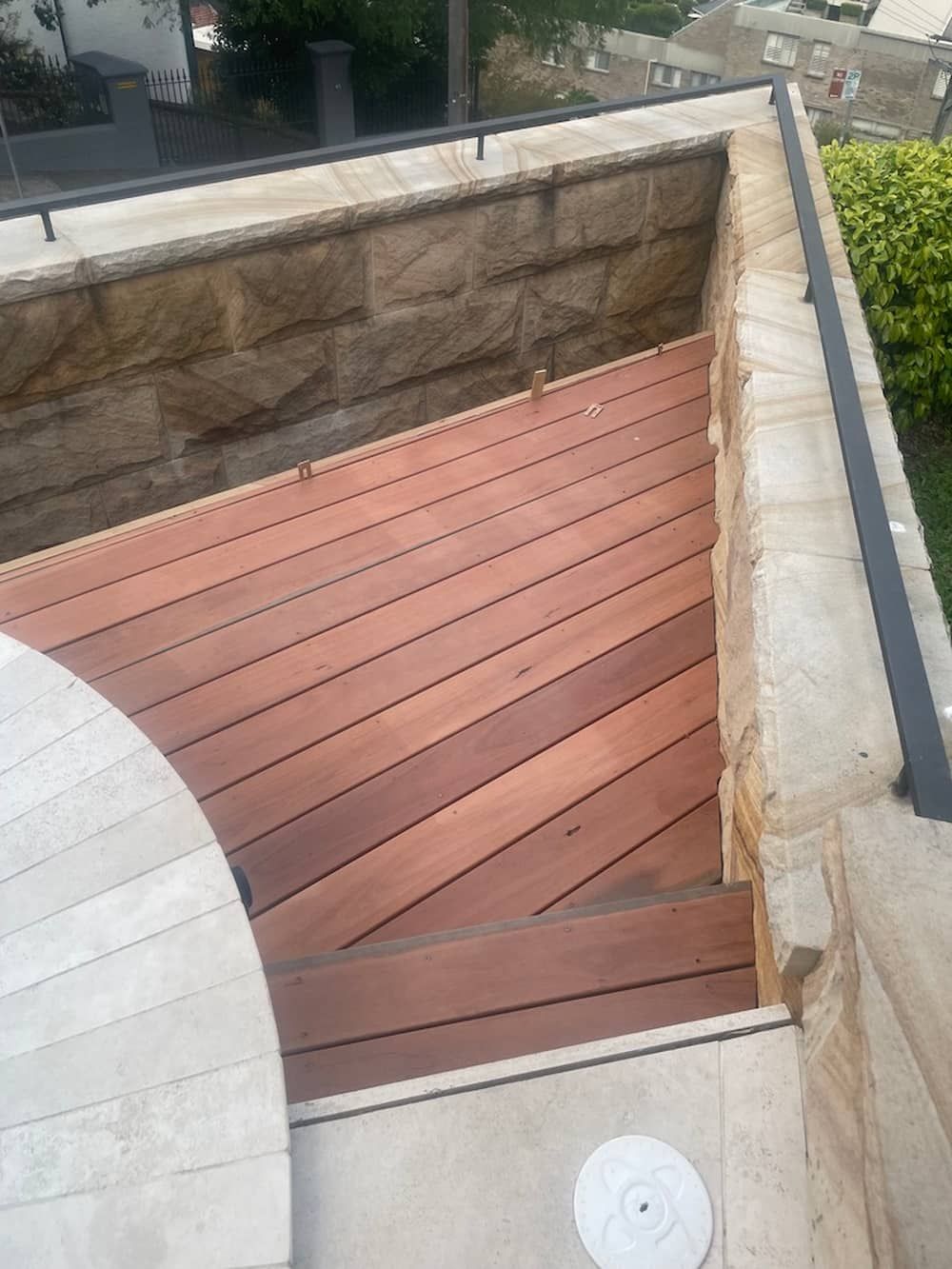 Wooden deck with stairs built into a sandstone and stone-tiled wall. — Gary Eslick Home Improvements In Berkeley Vale, NSW