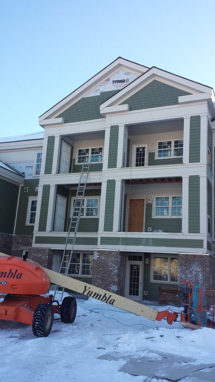 A large apartment building with a jlg lift parked in front of it.
