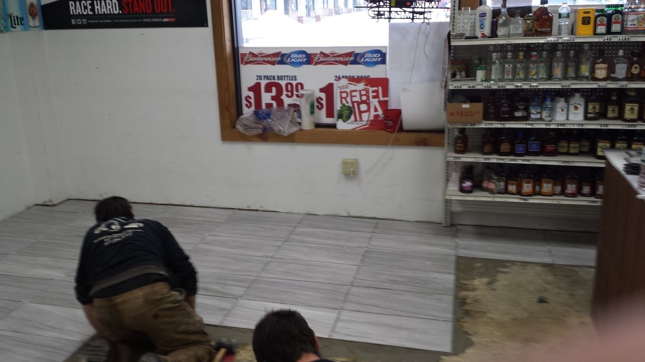Two men are kneeling on the floor in a store with a sign that says $ 3.99