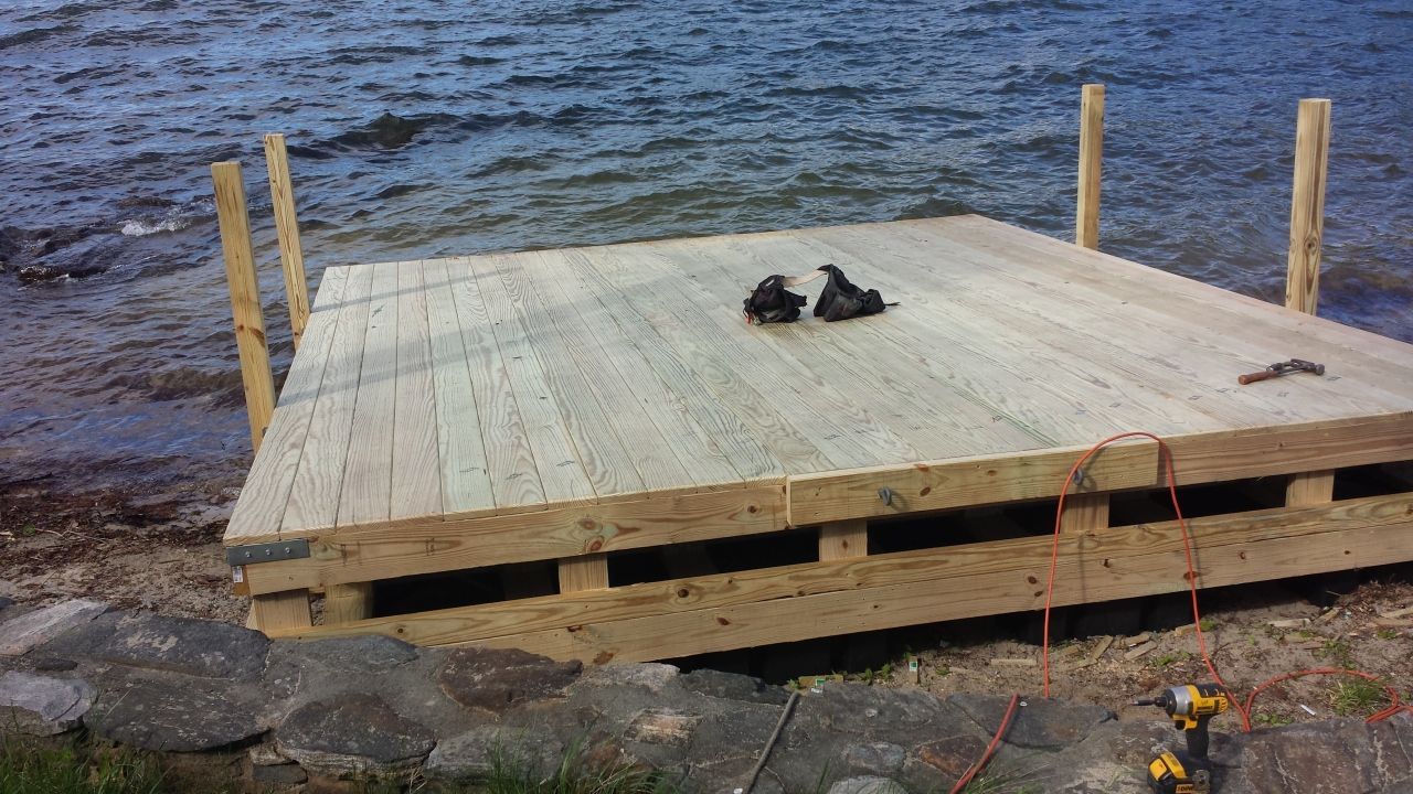 A wooden dock is being built on the shore of a lake.