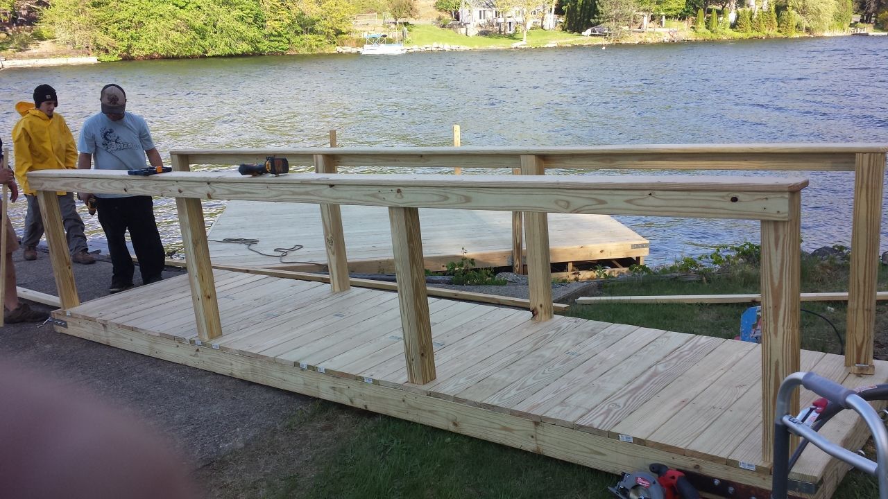A group of men are building a wooden bridge over a lake.