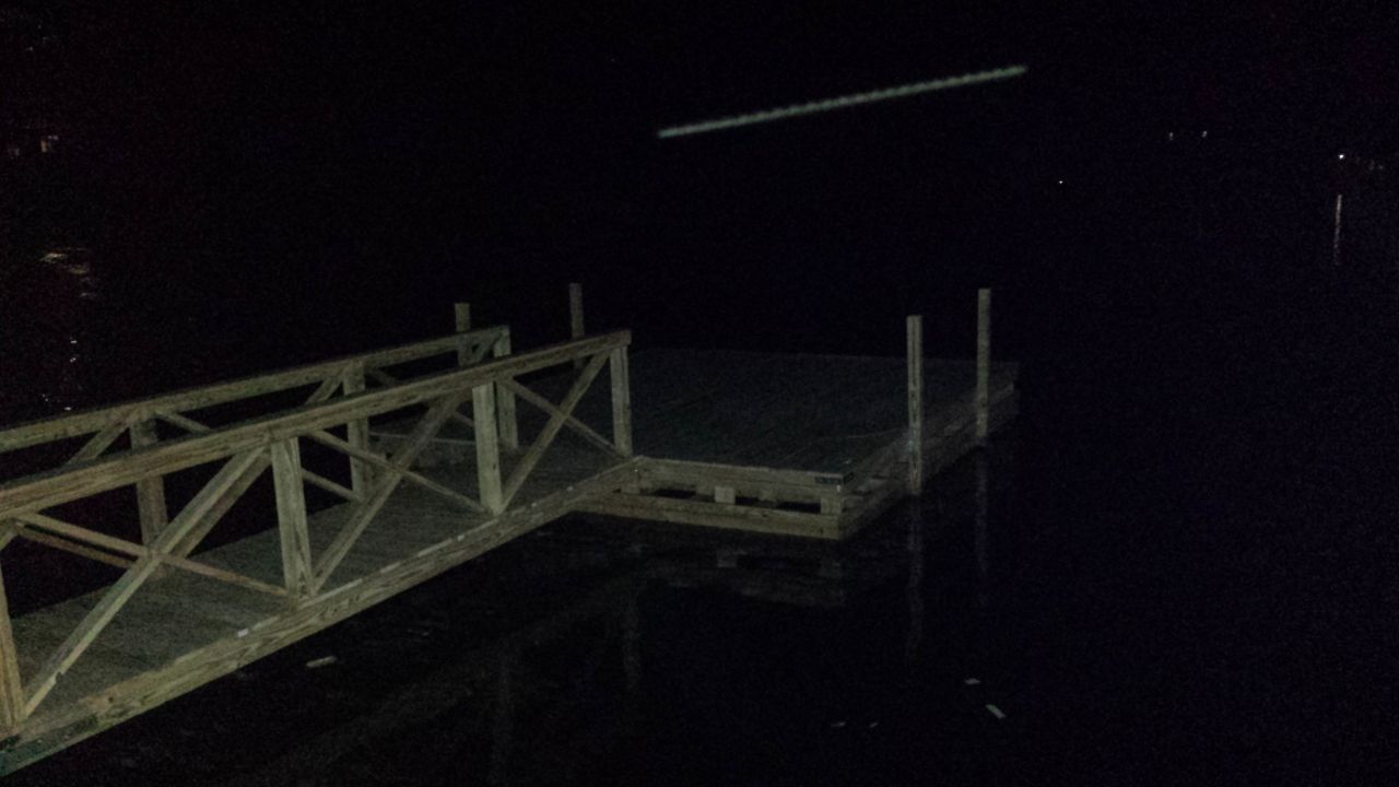 A dock in the middle of a body of water at night.